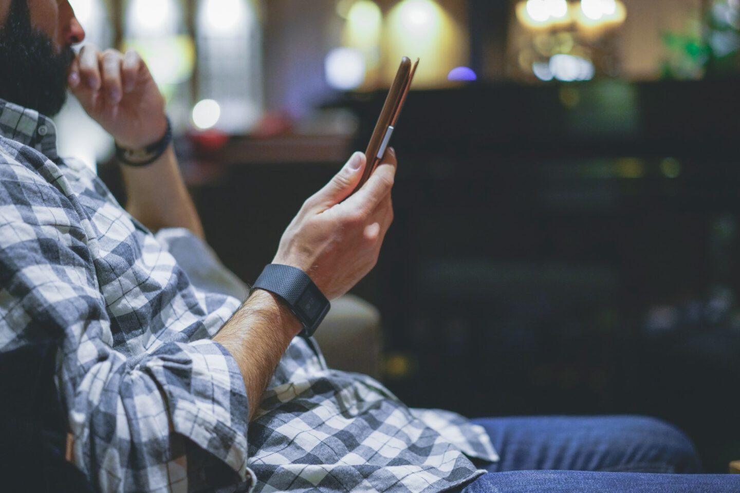 Handsome bearded man using electronic reader book computer while resting in lobby hotel.